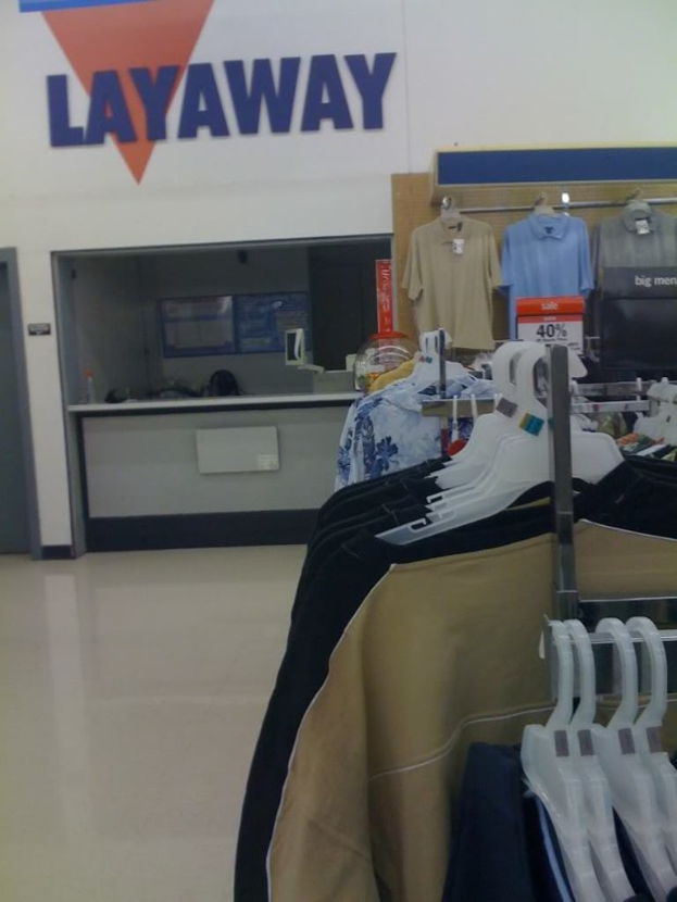 Ein Innenblick in einen Laden mit KÃ¤thren an BÃ¼geln, einem Tisch und einer Preisauszeichnungstafel.