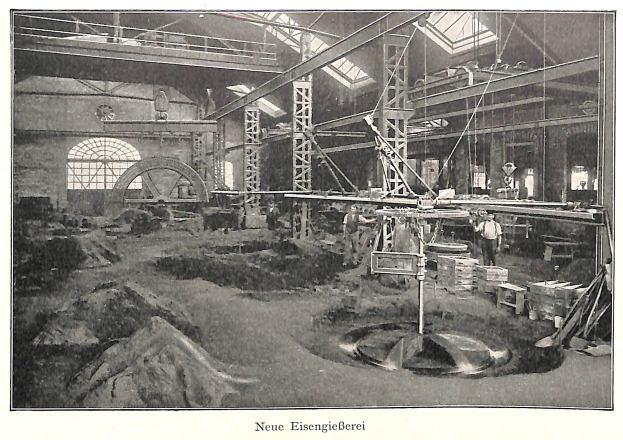 Black and white photograph of a factory interior with workers operating machinery, metal rods, and poles, labeled "New Eisenglebeerei, the first factory in Germany" at the bottom.