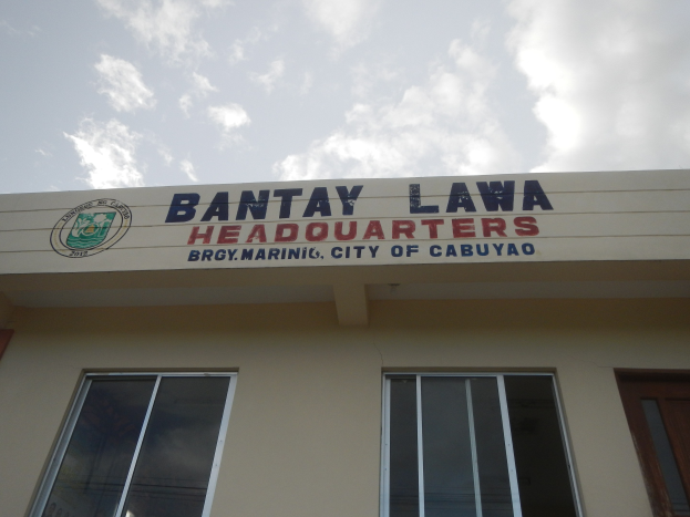 Die Zentrale der Bantay Lawa in Cebu City, Philippinen, ein Gebäude mit Fenstern, einer Tür und einer Namensschild an der Wand, unter einem Himmel mit weißen Wolken.