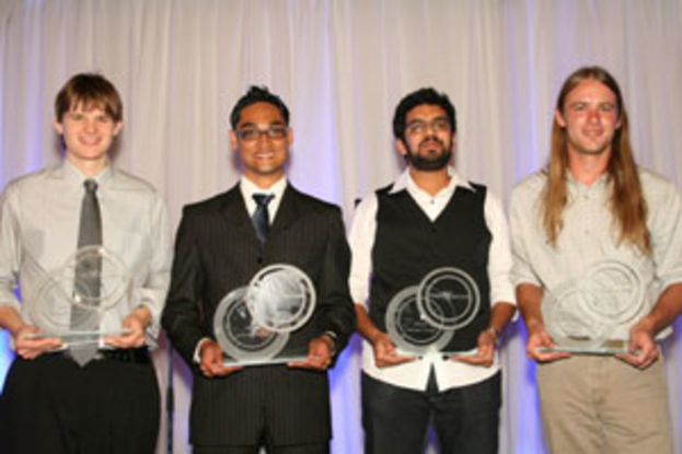Vier Personen mit strahlenden Gesichtern, jede hält einen Pokal in der Hand, vor einem Vorhang.