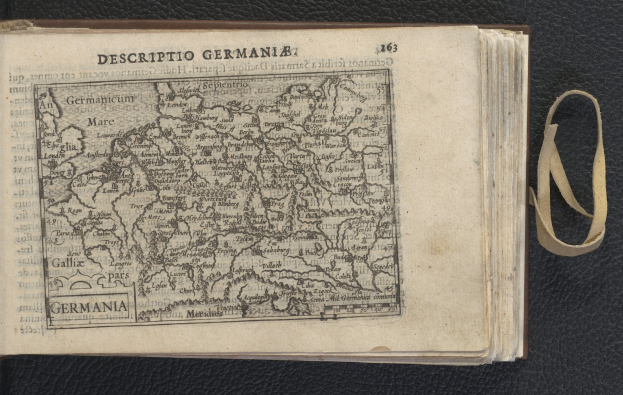 Offenes Buch mit einer Deutschlandkarte auf einer schwarzen Oberfläche, das eine Seite mit Text und einer historischen Karte zeigt.