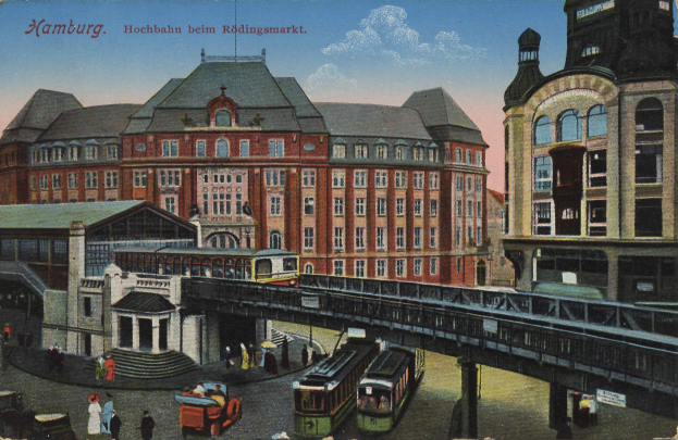 Eine alte Postkarte, die einen Bahnhof in Hamburg, Deutschland, mit Menschen, Fahrzeugen, Gebäuden, einer Brücke und einem bewölktem Himmel zeigt, zusammen mit Text überall.
