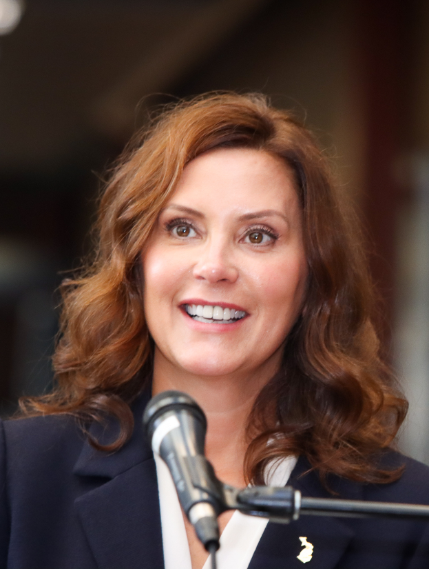 Michele Bachmann, gekleidet in Anzug und Krawatte, spricht in ein Mikrofon mit einem unscharfen Hintergrund.