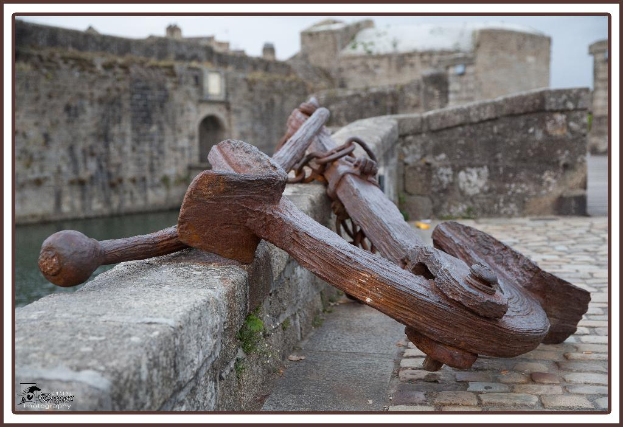 Ein Denkmal steht in der Nähe eines Sees mit einem klaren Himmel darüber und hölzernen Brettern im Vordergrund.