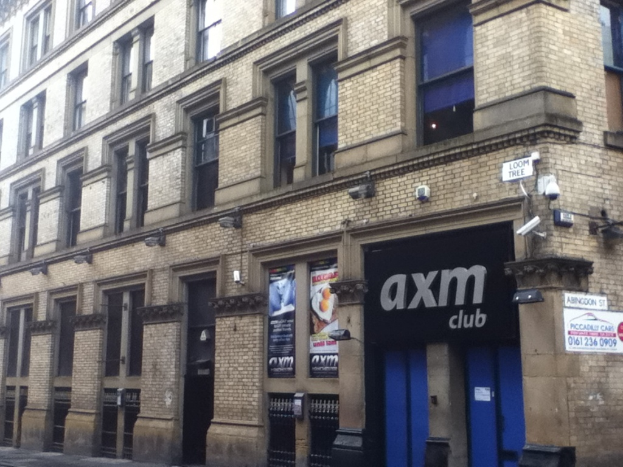 Ein Schaufenster mit Plakaten an dem Gebäude im Vordergrund.