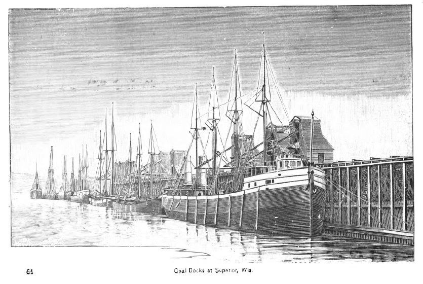 Schwarzes und weißes Foto von Kohledocks in Superior, Washington, mit Schiffen auf dem Wasser und einer Brücke auf der rechten Seite; Text unten.