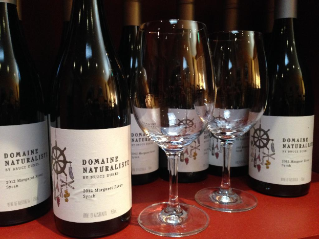 Mehrere Flaschen und zwei Weingläser sind auf einer roten Oberfläche platziert.