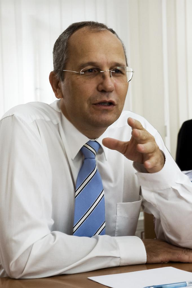 Eine Person, die auf einem Stuhl sitzt und ein Blatt Papier und einen Stift auf dem Tisch vor sich hat.
