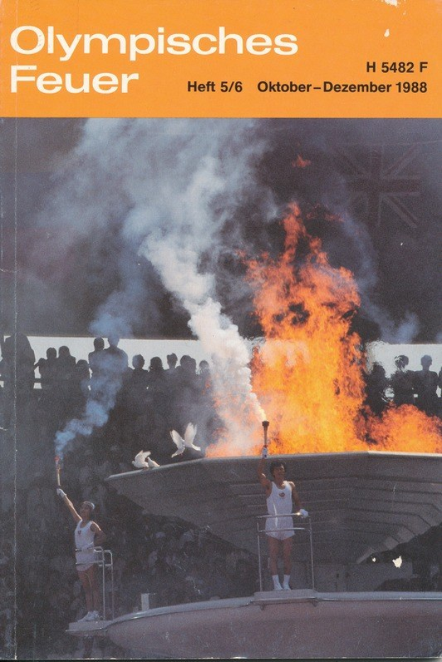 Buchumschlag mit dem Titel "Olympische Spiele Feuer - Heft 5/6 Oktober-Dezember 1988" mit zwei Personen, die Fackeln über einem Feuer halten, und einer Menge im Hintergrund.
