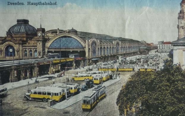 Black and white postcard of Dresden Hauptbahnhof train station in Germany, showing a busy street scene with vehicles, pedestrians, trees, buildings, and a cloudy sky.