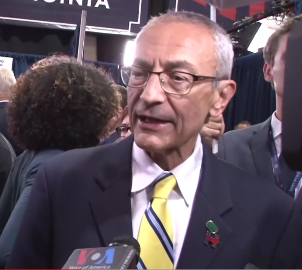 Senator Chuck Schumer in Anzug und Krawatte spricht zu Reportern an einem Podium mit dem Text "Sen. Schumer sagt, er sei 'kein Demokrat'".